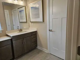 A modern bathroom with sleek dark cabinetry, light countertops, and elegant framed artwork.