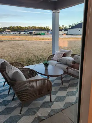 A cozy outdoor patio with modern seating, a geometric rug, and a view of a developing residential area.