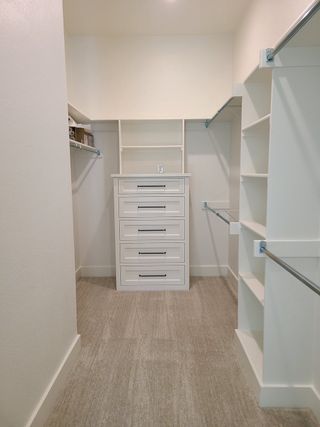 Model Home A spacious walk-in closet with built-in drawers, shelving, and sleek hanging rods, perfect for organized storage.