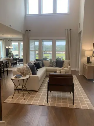 An elegant living room with a cozy sofa, chic armchair, and large windows providing natural light and serene views.