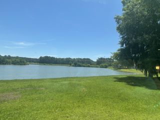 A picturesque lake view with lush greenery and trees in Timothy Lakes by Center Park Homes (Ridgeville, SC).