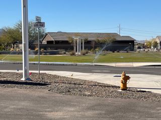 A modern home with a well-kept lawn and sprinklers in McClellan Ranch by Pulte Homes (Laveen, AZ).
