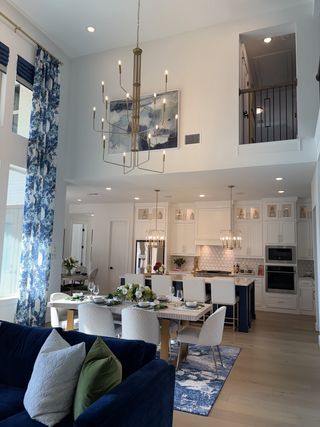A contemporary open-plan living area with elegant lighting, a navy blue sofa, and a stylish kitchen featuring modern accents.