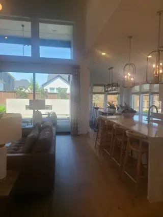 Bright open-concept living area with high ceilings, large windows, and sleek kitchen island with bar seating.