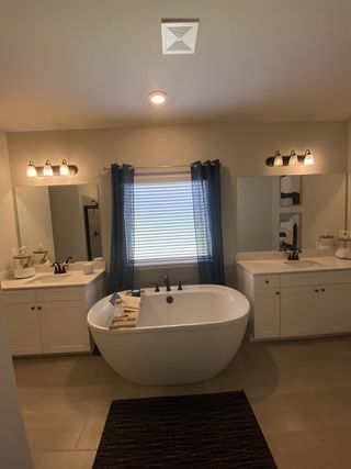A modern bathroom with a freestanding tub, dual vanities, and sleek lighting above large mirrors.