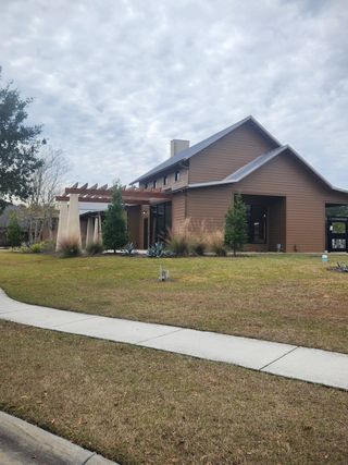 A contemporary brown home with sleek lines and landscaped surroundings in Panther Creek by Brightland Homes (Jacksonville, FL).