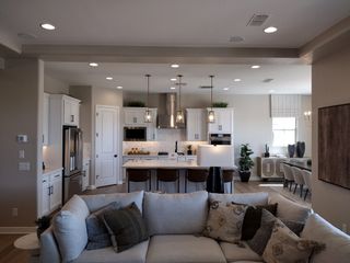 A modern open-concept living space with a cozy sectional, sleek kitchen island, pendant lights, and elegant dining area.