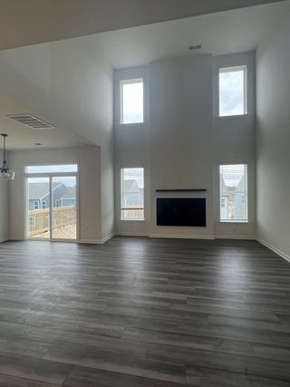 An open living area with high ceilings, large windows, a modern fireplace, and sleek flooring, perfect for natural light.