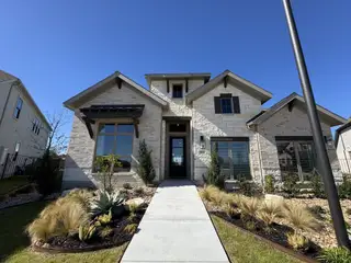 A beautiful stone facade home with manicured landscaping in Legacy at Lake Dunlap 50' by Perry Homes (New Braunfels, TX).