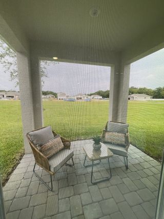 A cozy outdoor patio with wicker chairs and a small table overlooking a lush green backyard.