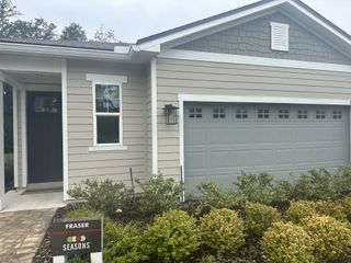 A charming beige home with a gray garage and neat landscaping in Seasons at Marietta Cove by Richmond American Homes (Jacksonville, FL).