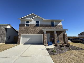 Street view A beautiful brick home with a spacious garage and manicured lawn in Eastwood at Sonterra: Cottage Collection by Lennar (Jarrell, TX).