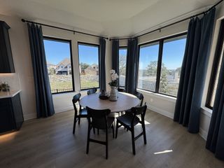 A bright breakfast nook with large windows and elegant navy curtains, offering a serene dining space with scenic outdoor views.
