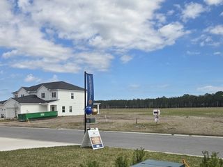 A spacious two-story white house amid open land in Brook Forest by Dream Finders Homes (St. Augustine, FL).