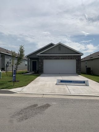 A modern gray home with brick accents and a tidy lawn in Sonterra by Starlight Homes (Jarrell, TX).