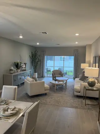 A cozy living room with neutral tones, stylish furniture, elegant lighting, and a view to the backyard patio.