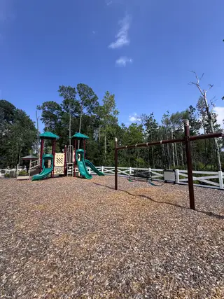 A vibrant playground surrounded by lush greenery in Jennings Farm by Dream Finders Homes (Middleburg, FL).
