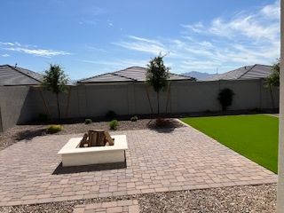 A serene backyard with a firepit, paver patio, and artificial grass, offering mountain views.