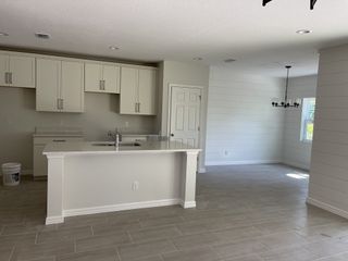A modern kitchen with sleek white cabinetry, subway tile backsplash, and a breakfast bar in an open-plan layout.