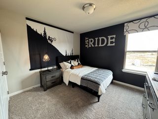 Model Home A modern bedroom with a cycling-themed mural, cozy bedding, and a stylish lamp on a dark wood nightstand.