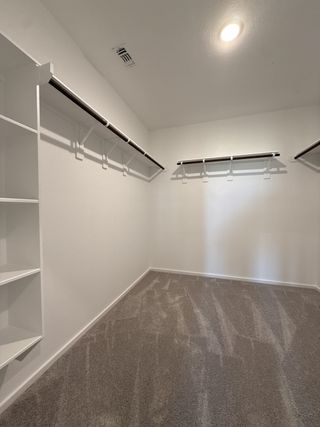 A spacious walk-in closet with ample shelving, carpeted flooring, and bright lighting for ultimate organization.