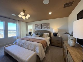 Model Home A cozy bedroom featuring a soft bed, elegant lighting, and natural wood accents.