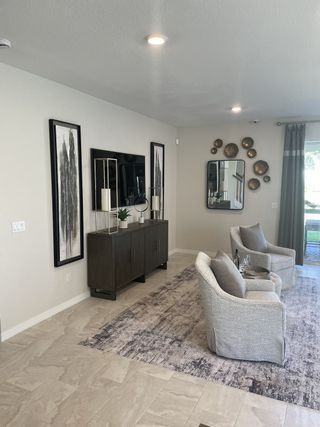 A chic living area with elegant armchairs, contemporary art, and a decorative console on a textured rug.