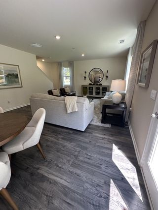 A cozy living room with a stylish gray sofa, dark wood floors, and modern decor accents.