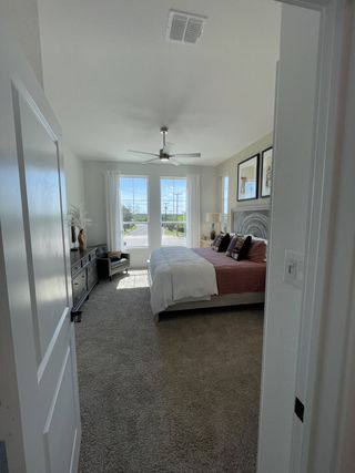 A cozy bedroom featuring a plush carpet, large windows, and modern decor for a serene ambiance.