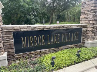 Elegant stone entrance sign for Mirror Lake Village by Park Square Residential in Fruitland Park, FL, surrounded by greenery.