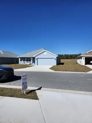 A charming blue home with a spacious driveway in Oak Hill Plantation by Adams Homes (Ocala, FL).