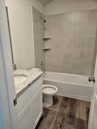 A modern bathroom with textured tile walls, granite countertops, and wood-style flooring for a sleek, contemporary look.