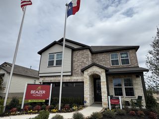 A modern stone and brick home with manicured landscaping in Hunter's Ranch by Beazer Homes, San Antonio, TX.