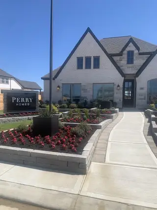 A charming white-brick home with manicured gardens in Amira 50' by Perry Homes (Tomball, TX).