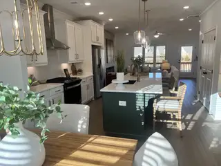 A bright, modern kitchen with white cabinetry, an island, and stylish lighting, offering a welcoming and airy ambiance.