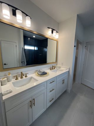 A sleek bathroom with dual sinks, gold fixtures, and modern lighting, offering elegant functionality and style.