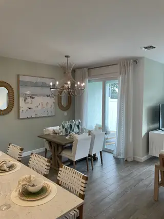 Model Home A chic dining area with elegant chandelier, sliding glass doors, and tasteful decor.