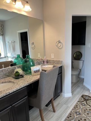 A modern bathroom with granite countertops, elegant lighting, and a cozy seating area.