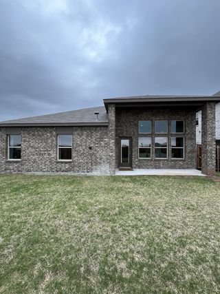 A modern brick home with expansive windows and a spacious yard in Liberty Crossing by D.R. Horton (Royse City, TX).
