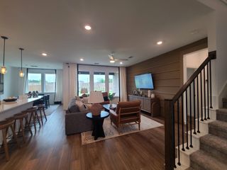 A modern living area featuring hardwood floors, cozy seating, and a sleek kitchen with pendant lighting.