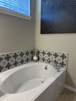 Model Home A modern bathroom featuring a sleek oval tub with patterned tiles and stylish wall art.