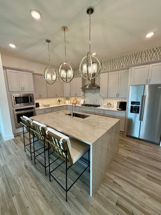 A modern kitchen with marble island, stylish pendant lights, and sleek appliances.