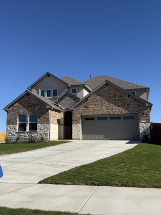 A beautiful brick home with a spacious driveway and manicured lawn in Rosenbusch Ranch by D.R. Horton (Leander, TX).