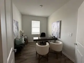 A sophisticated home office with a minimalist desk, cozy seating, and elegant artwork on the walls.