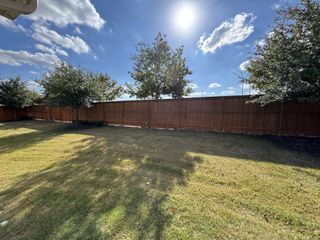 A spacious backyard with lush grass and a wooden fence in Crosswinds by Pacesetter Homes (Kyle, TX).