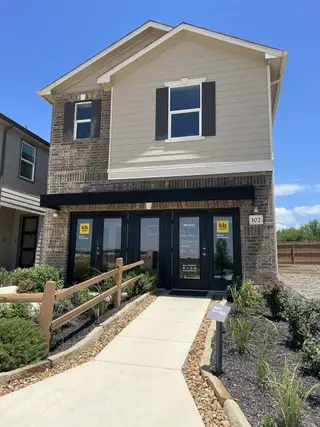 A modern two-story model home in Villas at Presidio by KB Home (San Antonio, TX), featuring a brick and siding exterior, a covered entryway, and a paved walkway.