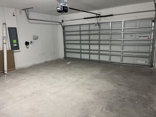 Model Home A spacious, modern garage with clean concrete floors and a large metal door. Ideal for storage or parking needs.