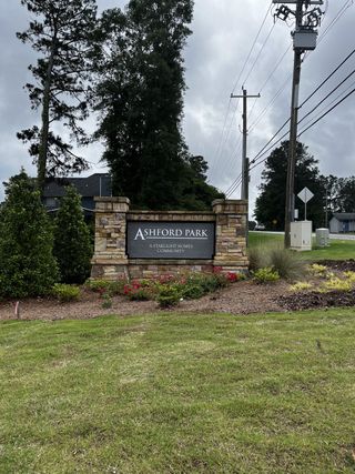 Street view A welcoming stone entrance sign surrounded by greenery at Ashford Park, a Starlight Homes community in Covington, GA.