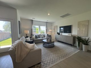 A cozy living room featuring a plush gray sofa, stylish rug, and large windows overlooking a lush green backyard.