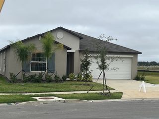 A charming new single-story home with a modern facade, palm trees, and a two-car garage in Mirada by Lennar (San Antonio, FL).